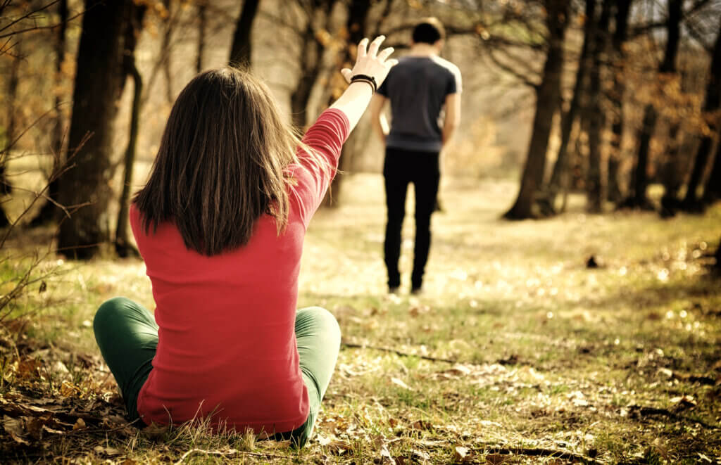 woman reaching out to man to come back after an argument